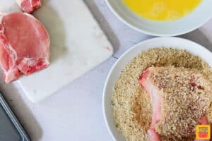 dipping bone in pork chop in breadcrumb mixture
