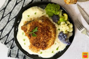 oven baked pork chop over mashed potatoes on a black plate