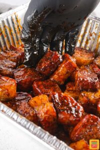 mixing pork belly burnt ends with bbq sauce
