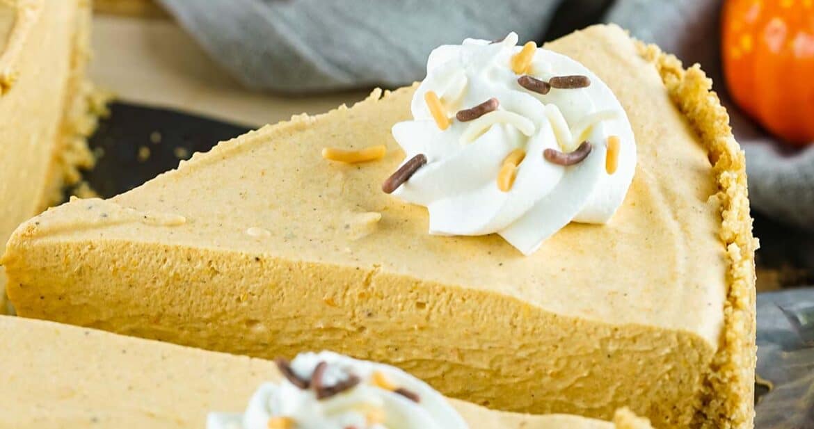 close up slice of pumpkin pie with whipped cream and sprinkles on top