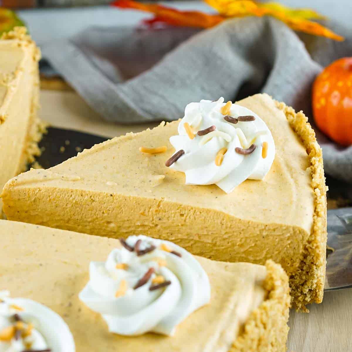 close up slice of pumpkin pie with whipped cream and sprinkles on top