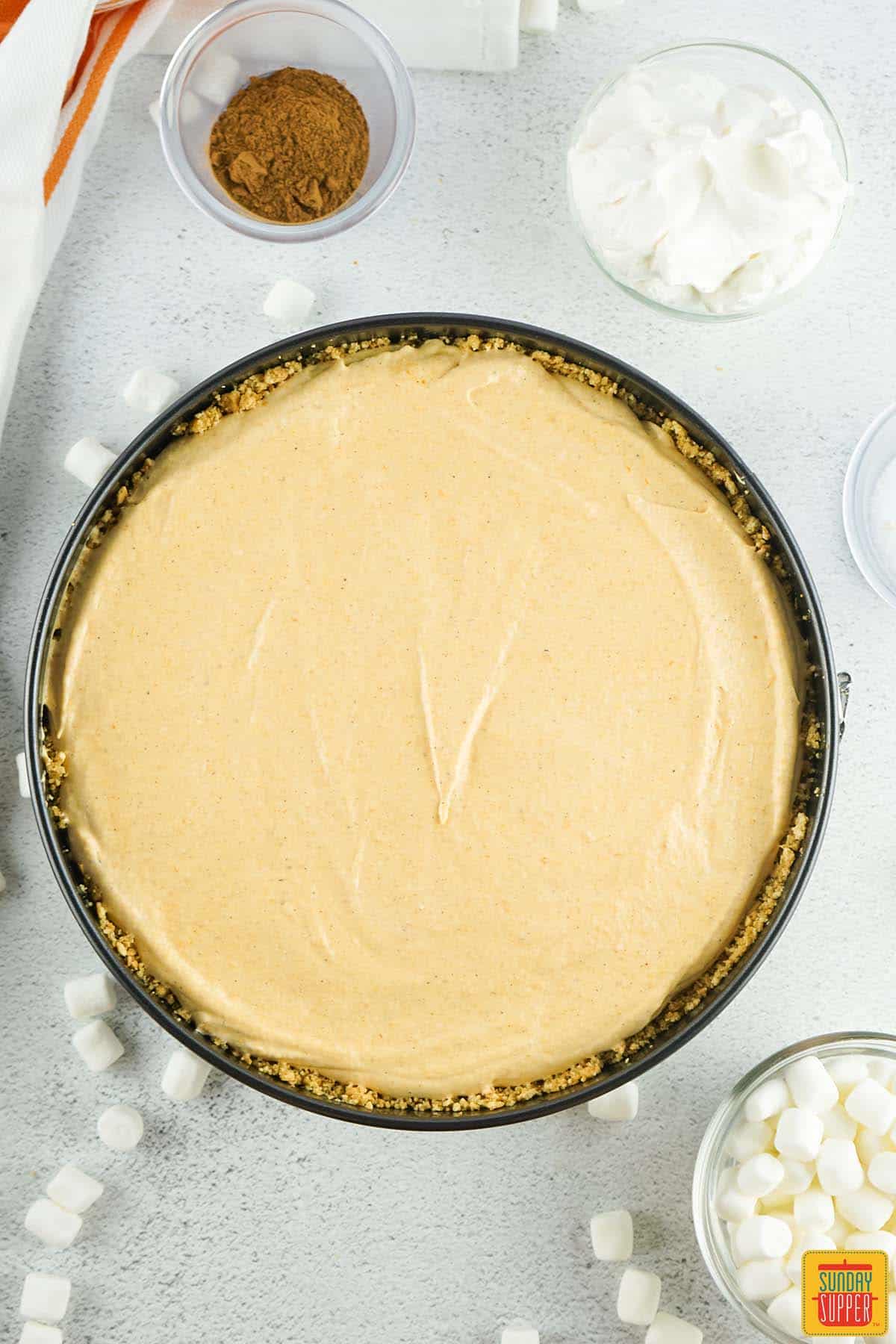 layering pumpkin pie filling into pan with crust