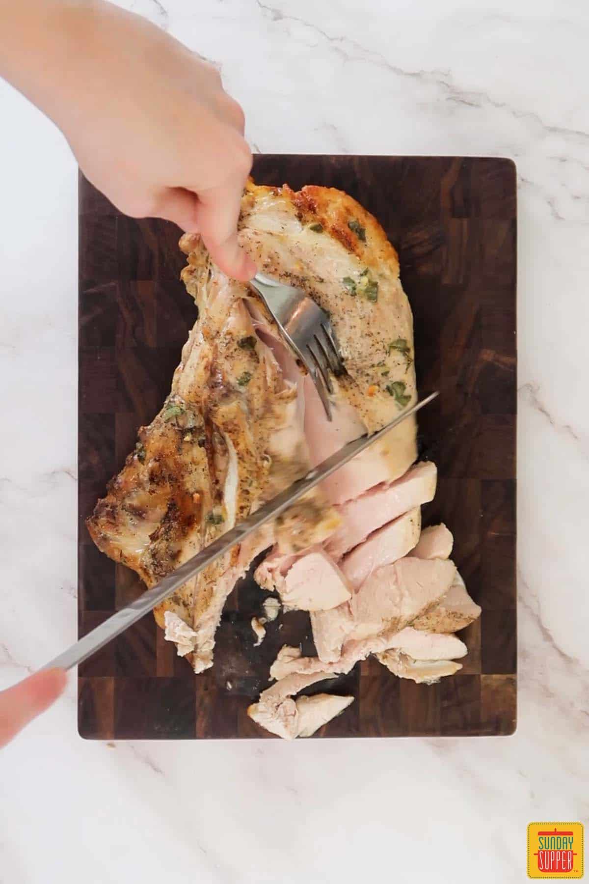 slicing sous vide turkey breast on a cutting board
