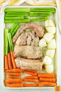 turkey, onions, celery, and carrots on a baking sheet