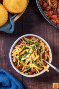 beef chili in a white bowl with cheese and cilantro
