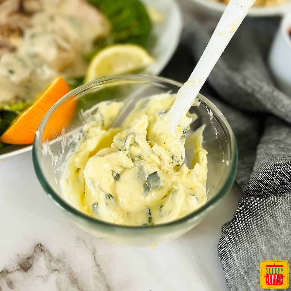 compound butter for turkey in a clear dish with a white spoon next to a turkey