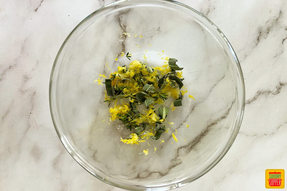 lemon zest and fresh thyme leaves chopped up in a small clear bowl