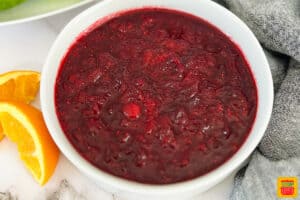 cranberry sauce in a white bowl with sliced oranges next to the bowl