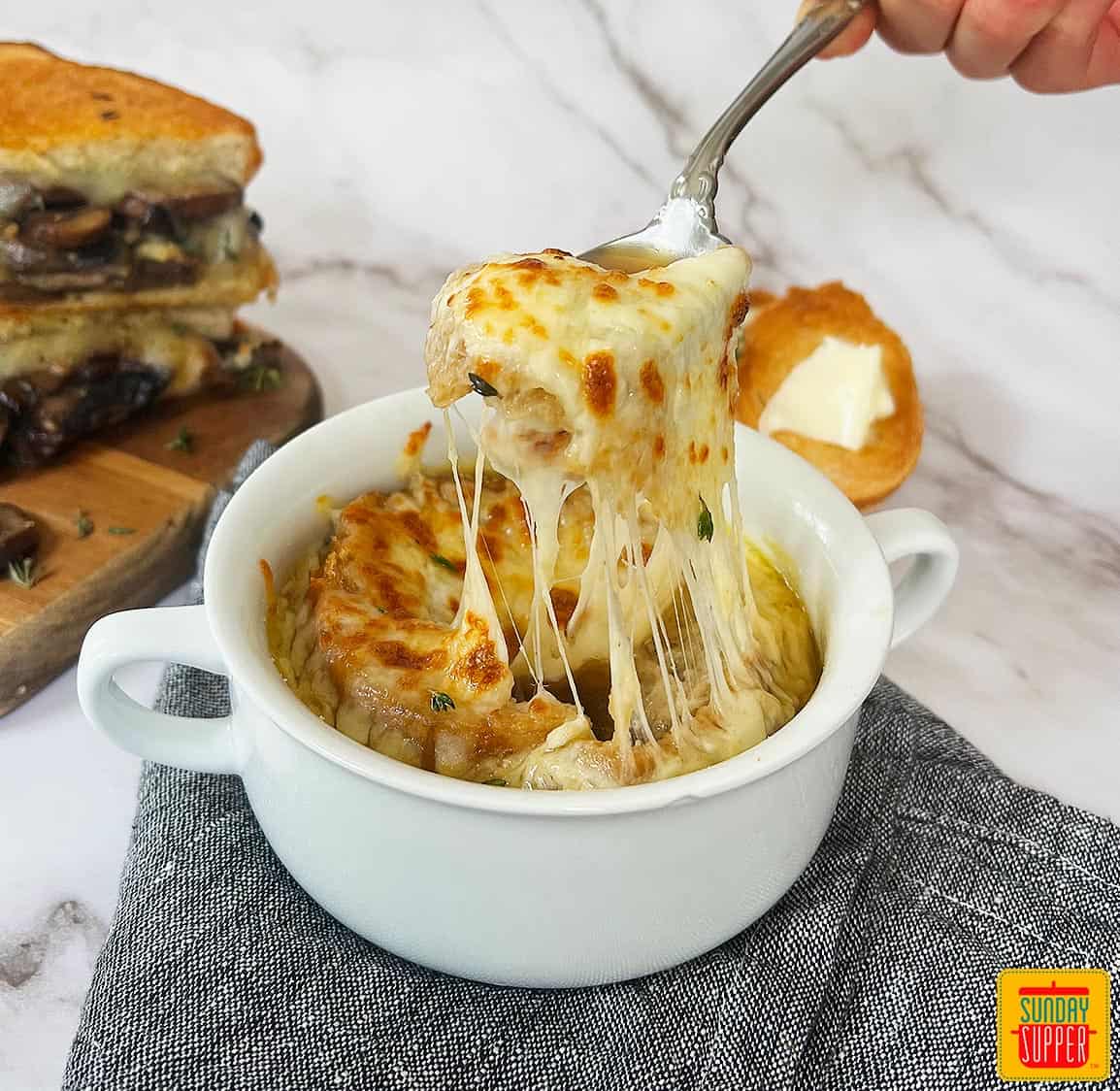 instant pot French onion soup in a white bowl with a spoon pulling up cheese