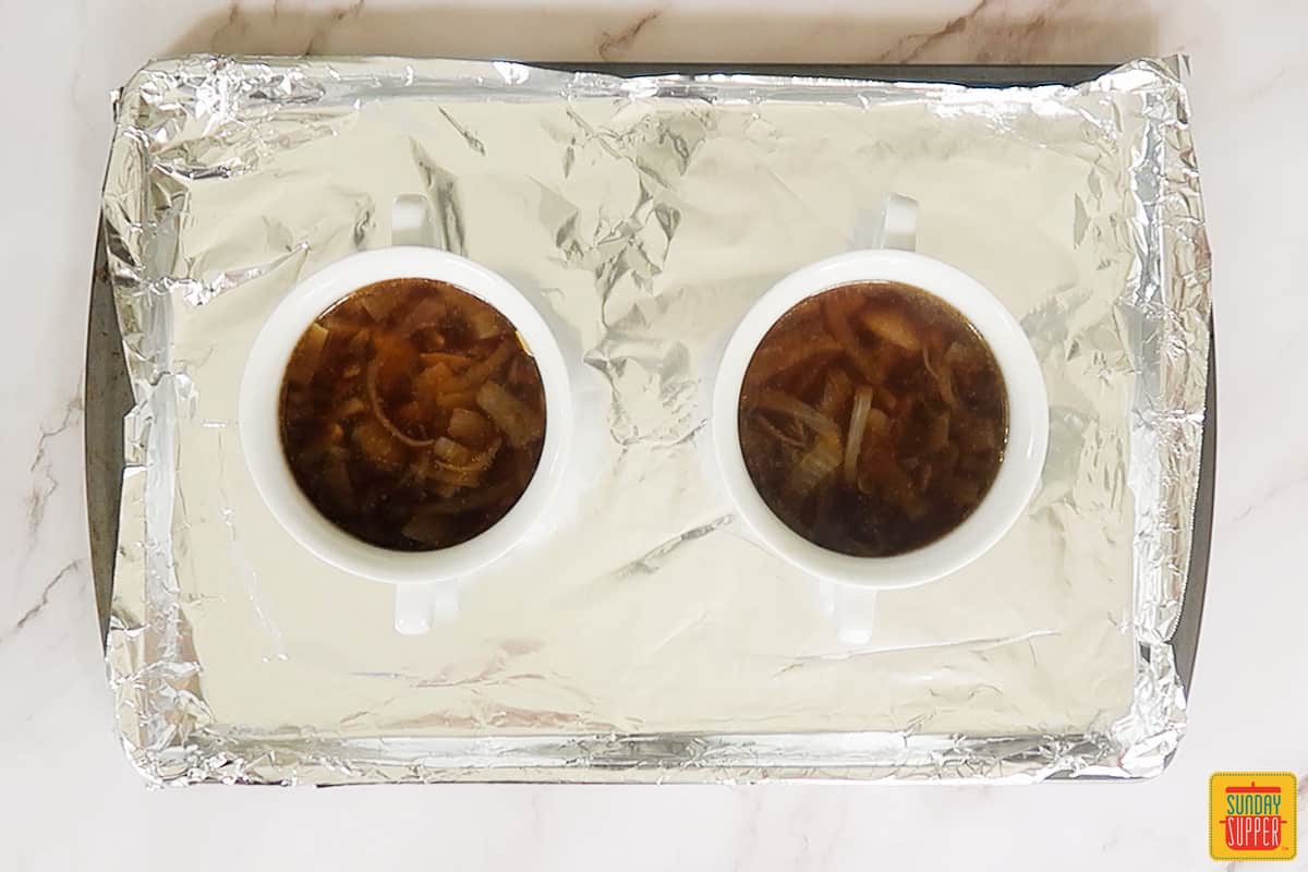 soup spooned into two white bowls on top of a baking sheet lined with aluminum foil