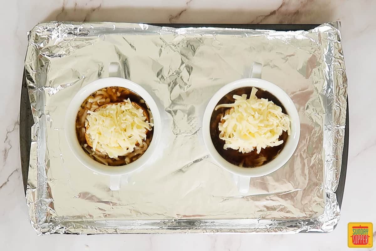 2 white bowls with French onion soup ready for the oven