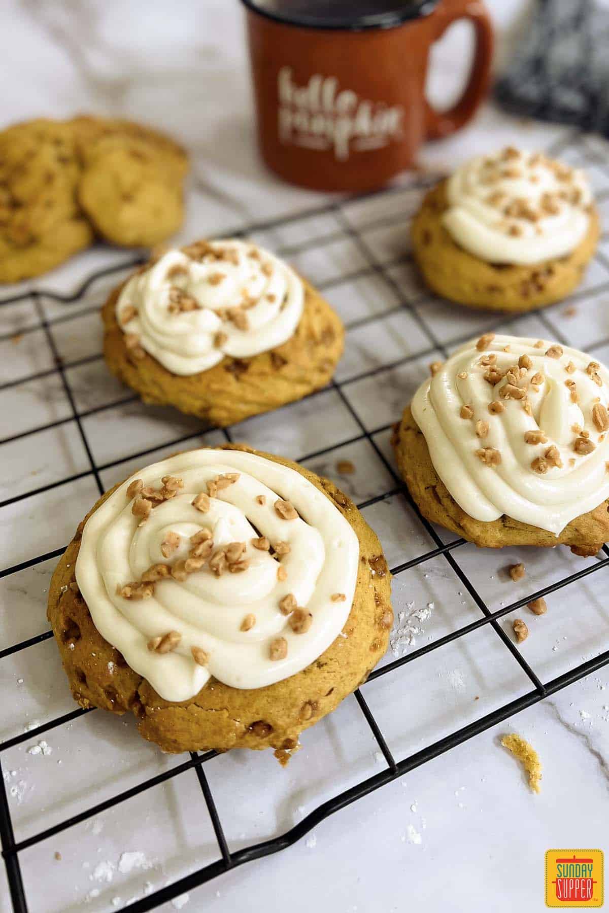cream cheese frosted pumpkin cookies on a baking rack