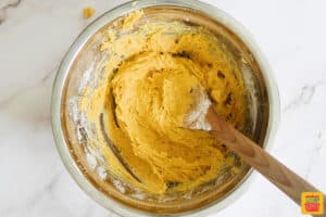 pumpkin pie cookie dough mixed together in a bowl with a wooden spoon