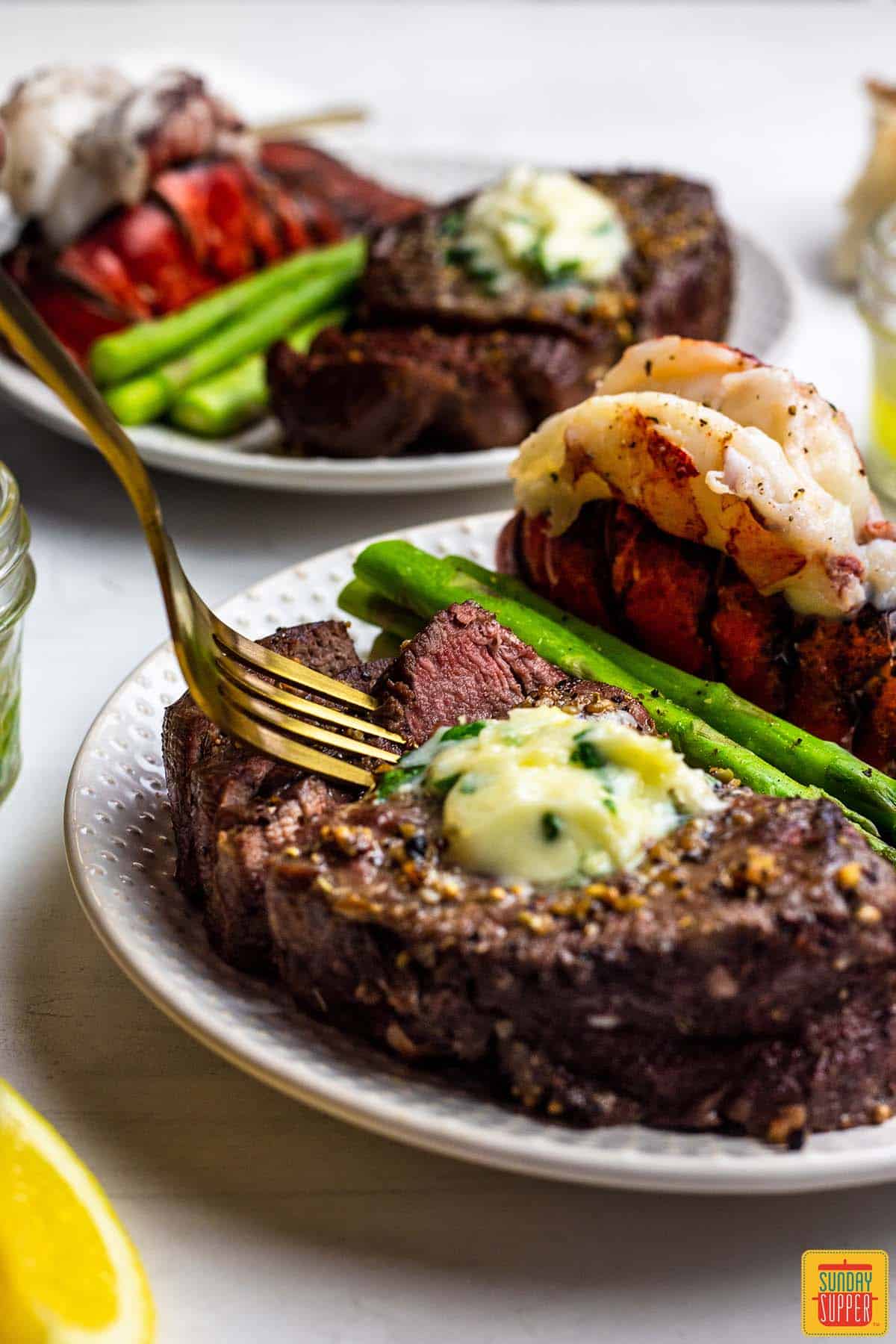 air fryer steak and lobster on a plate with asparagus and a fork
