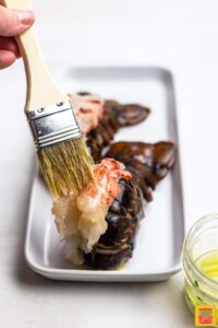Brushing garlic butter onto lobster meat
