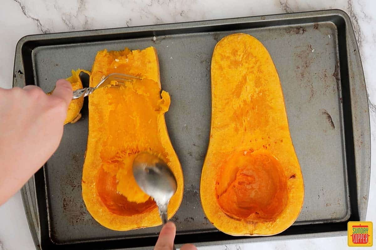 scooping out butternut squash after roasting