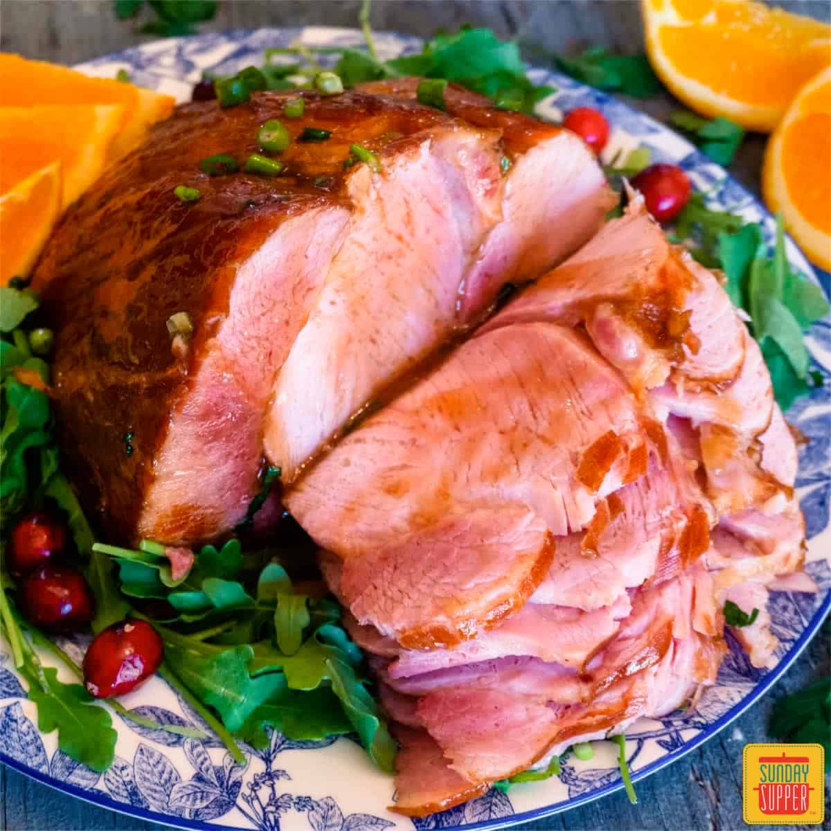 Close up of honey glazed ham slices with greens and oranges