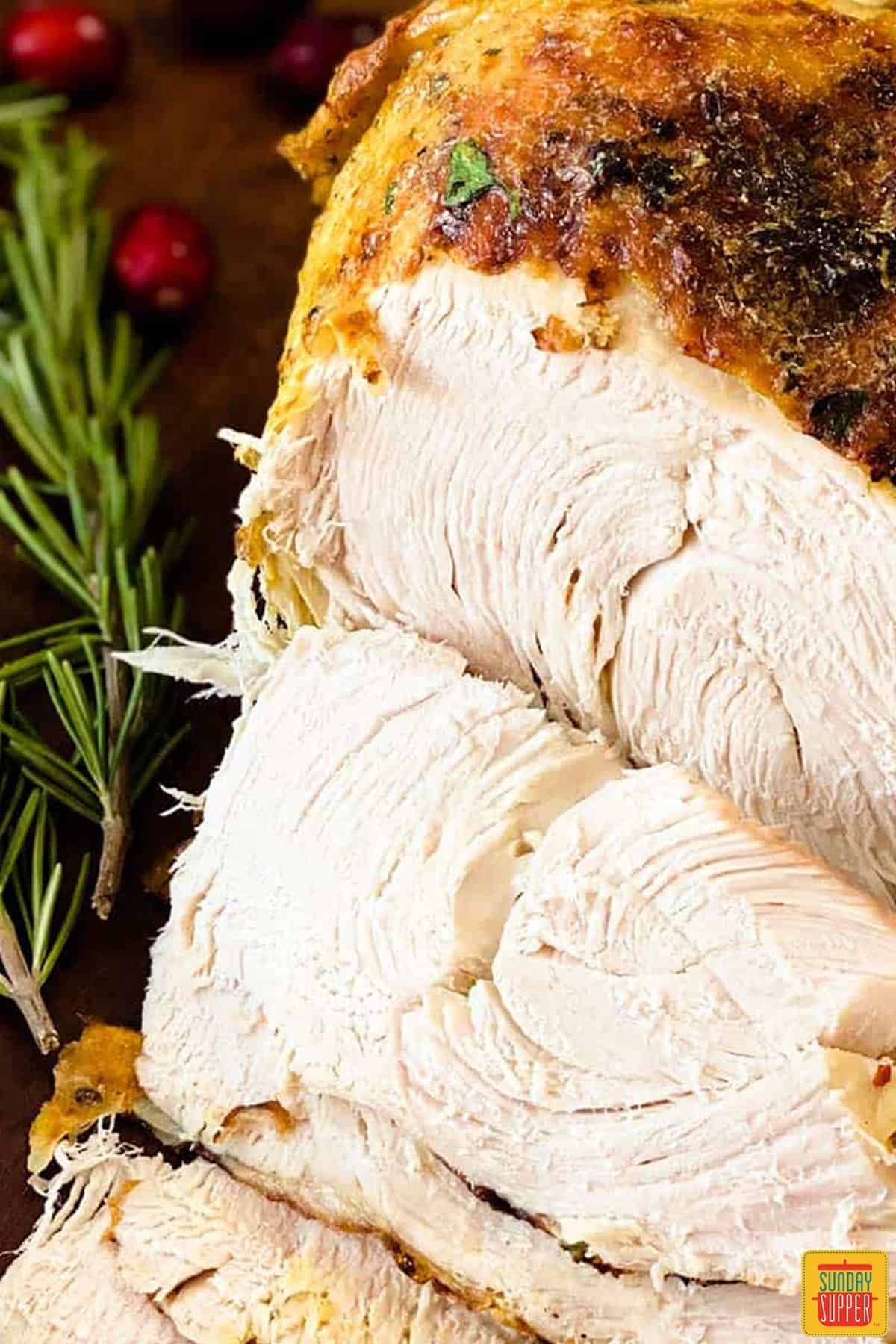 a closeup of sliced grilled turkey with rosemary and cranberries