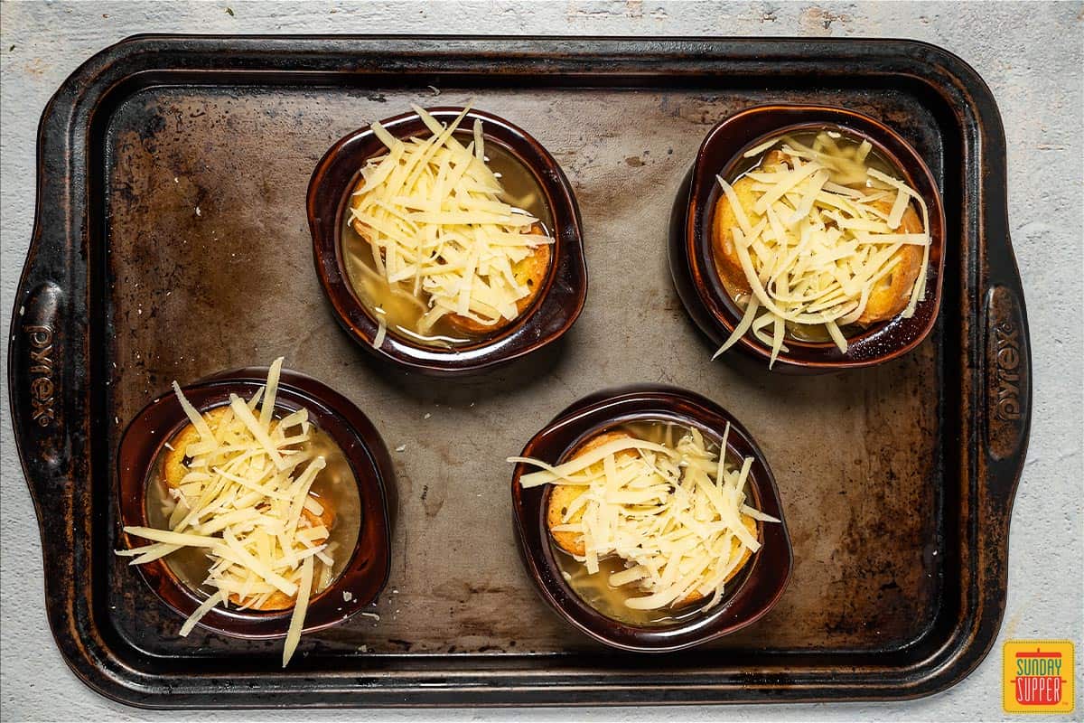 4 bowls of French onion soup on a baking sheet
