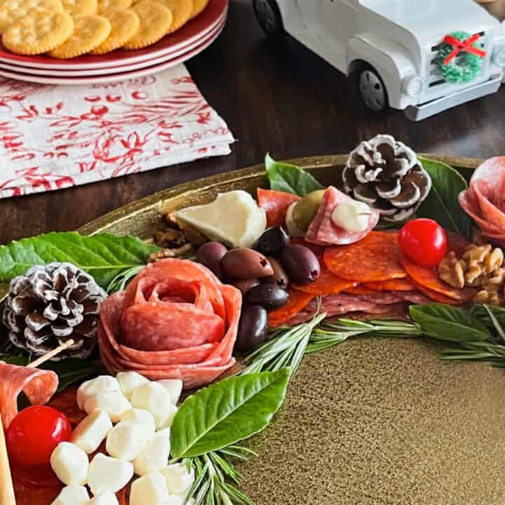 holiday charcuterie board with meats, cheeses, olives and decorative pinecones