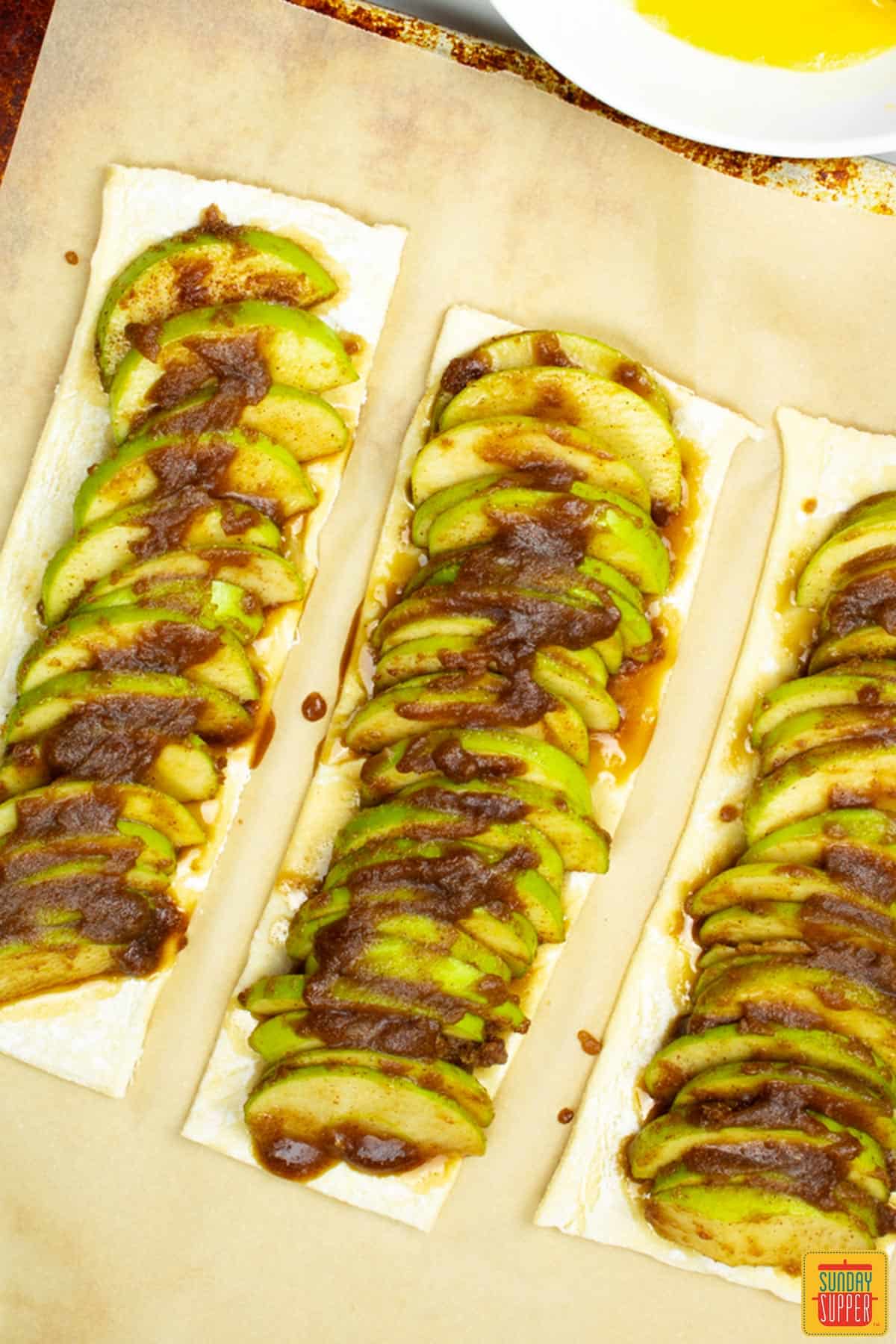 puff pastry with apples and sugar mixture on top on a baking sheet