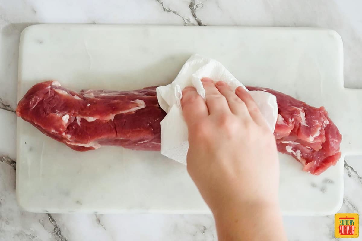 patting pork tenderloin dry with a paper towel