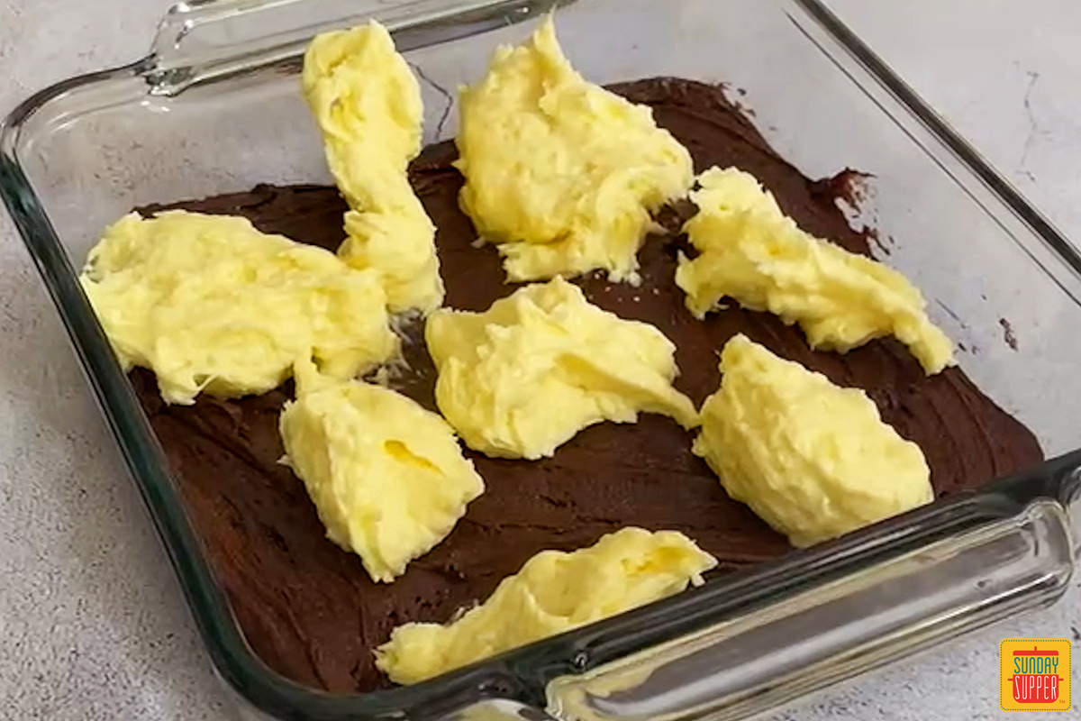 banana pudding dolloped over brownie mix in a clear baking dish