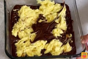 swirling banana pudding mix and brownie mix together in a clear baking dish