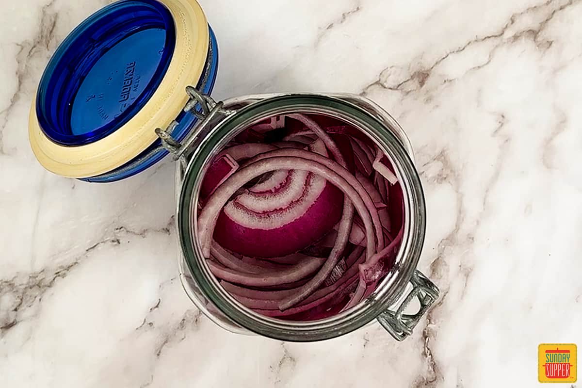sliced red onions in a clear mason jar