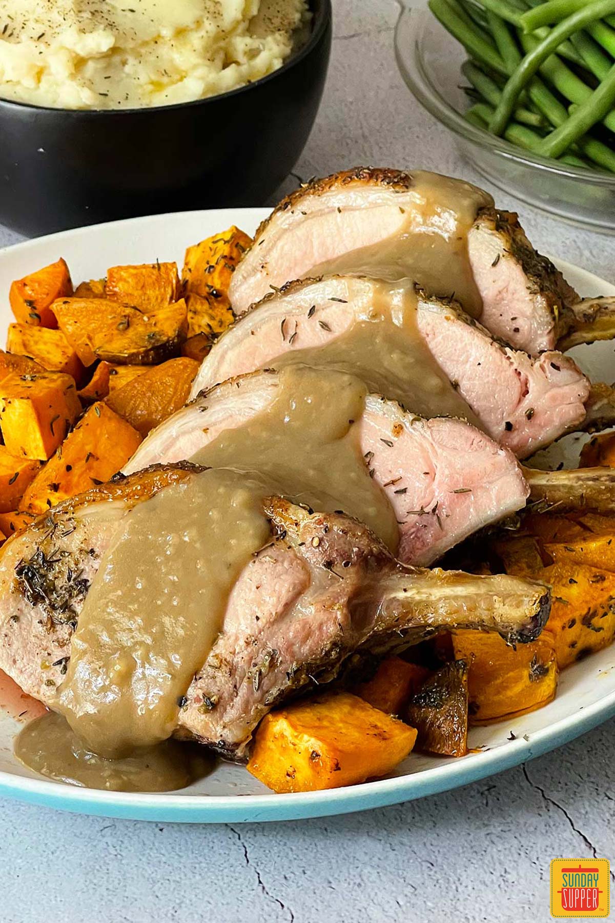 pork gravy poured overtop a pork roast on a white plate