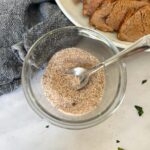 pork seasoning in a clear bowl with a metal spoon inside