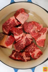 a dutch oven filled with large chunks of beef being browned