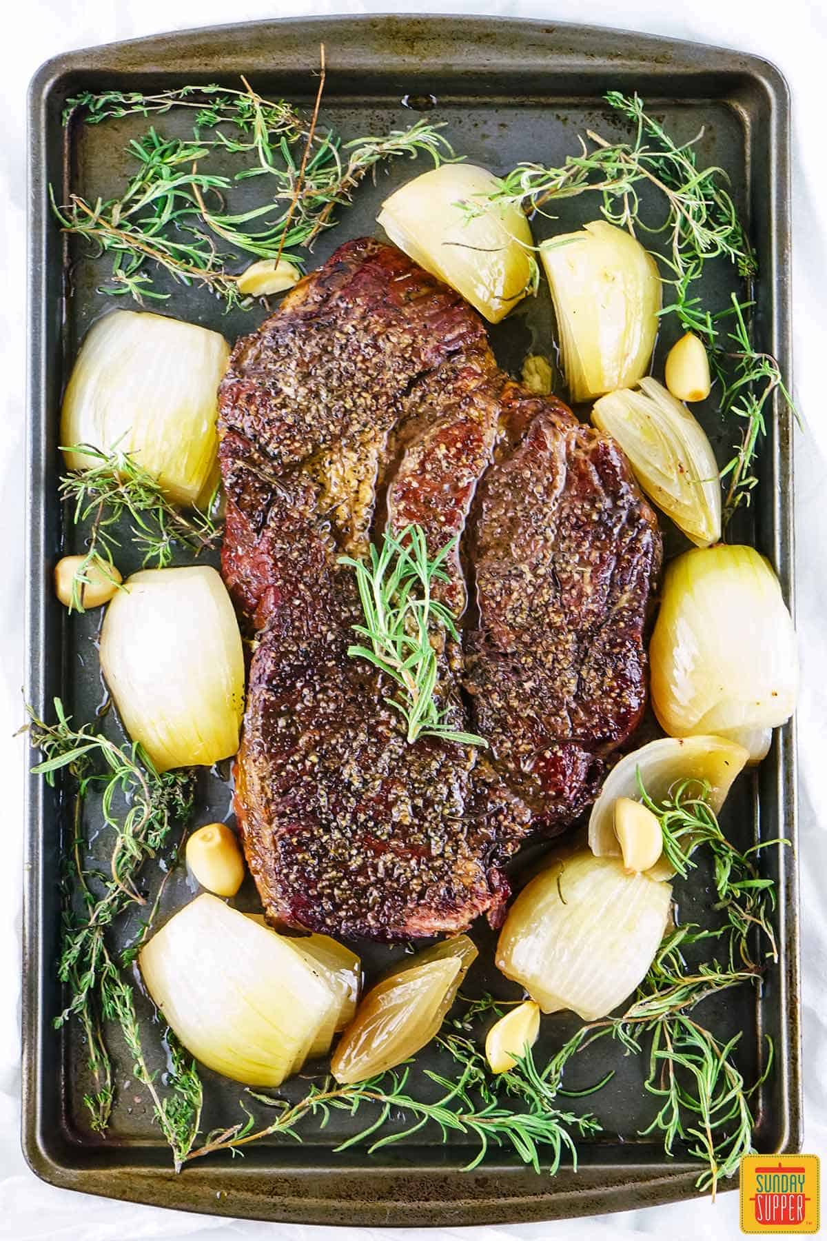 a smoked chuck roast with cooked onions and fresh rosemary