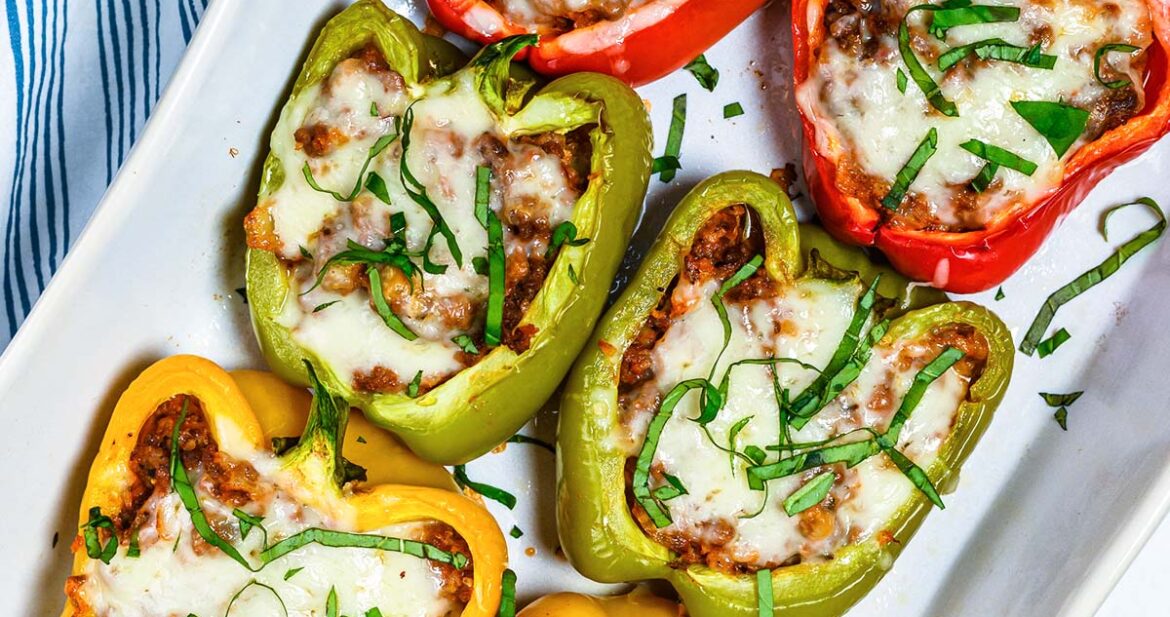 six stuffed bell peppers on a white baking dish