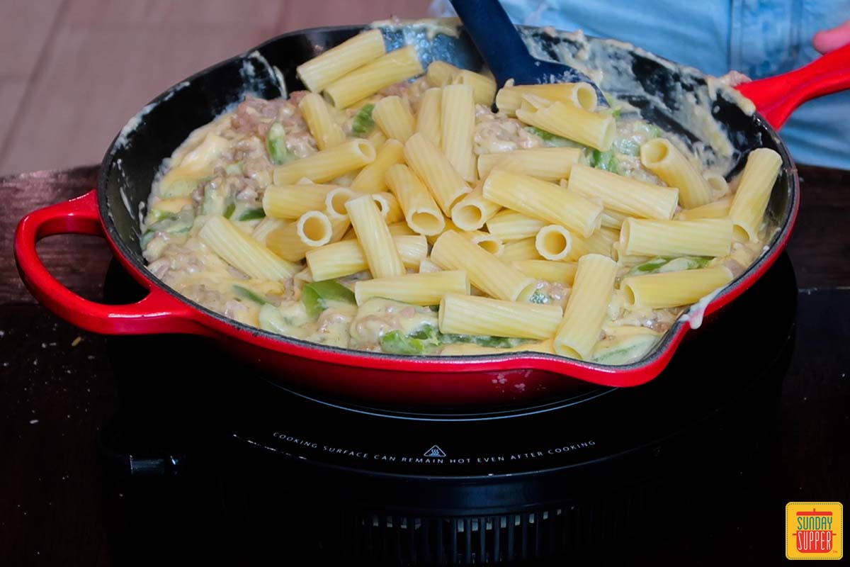 adding cooked ziti pasta to skillet