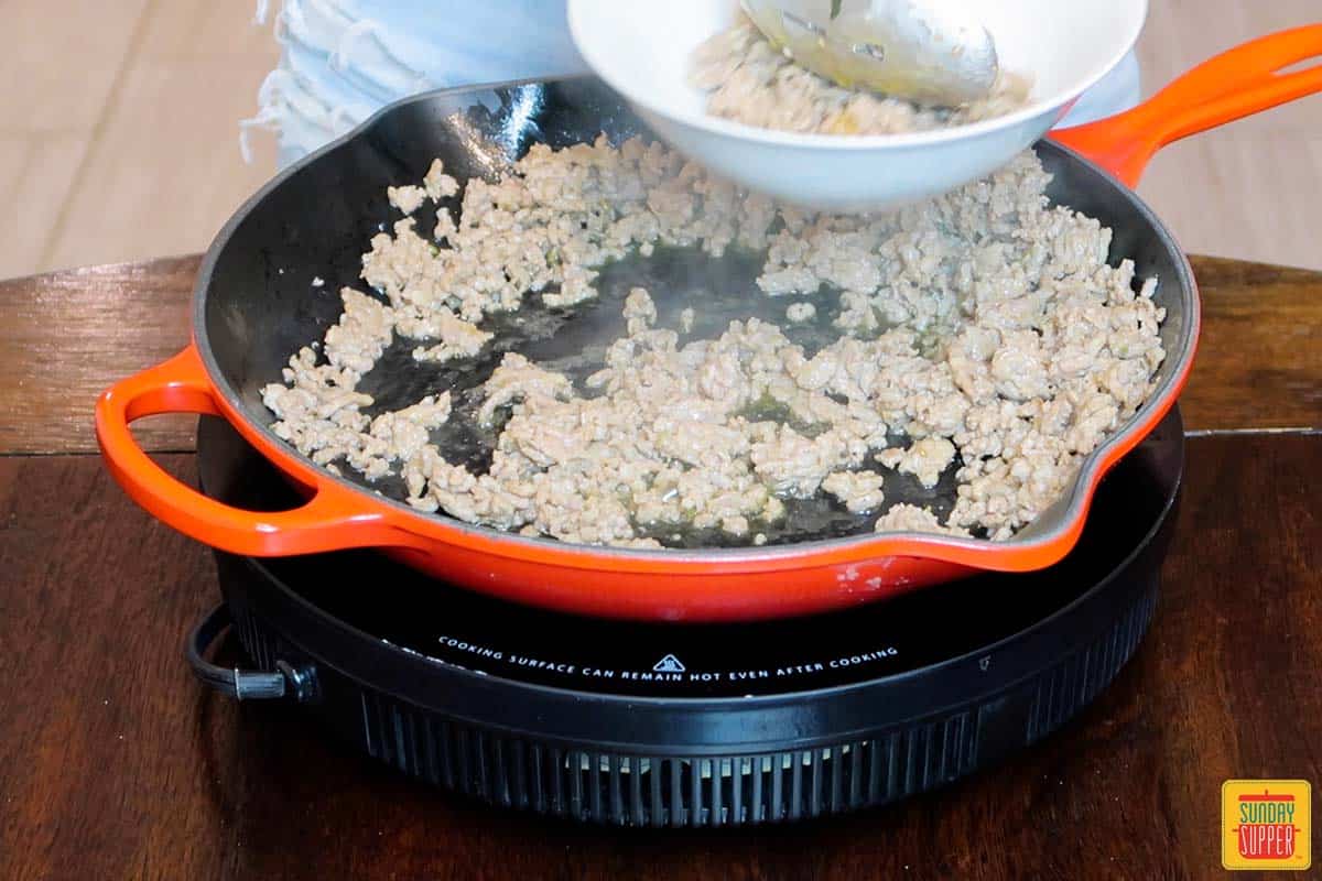 removing sausage from skillet with spoon