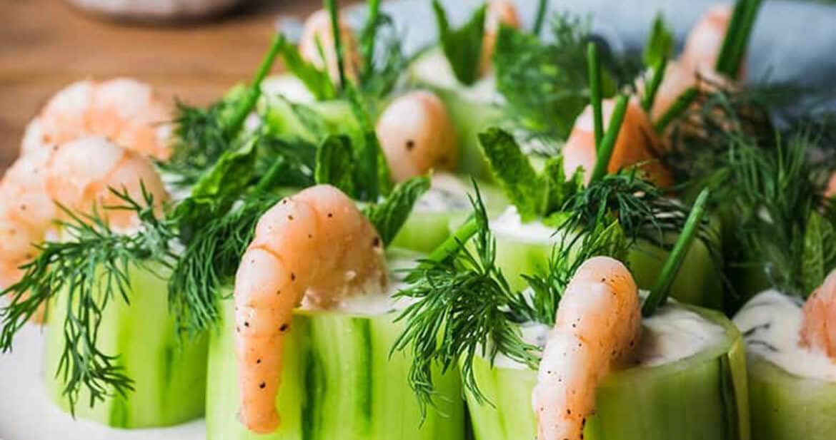 cucumber and shrimp canapes lined up on a white plate