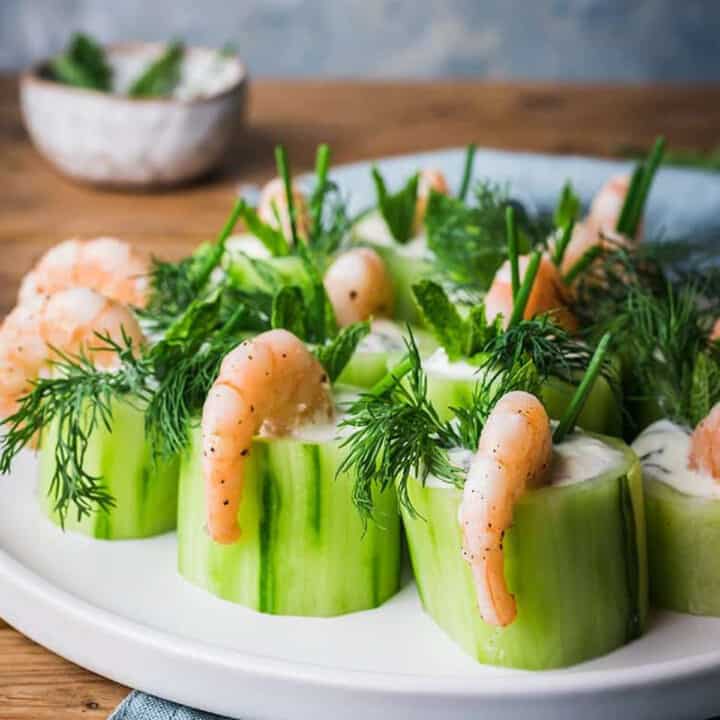 cucumber and shrimp canapes lined up on a white plate
