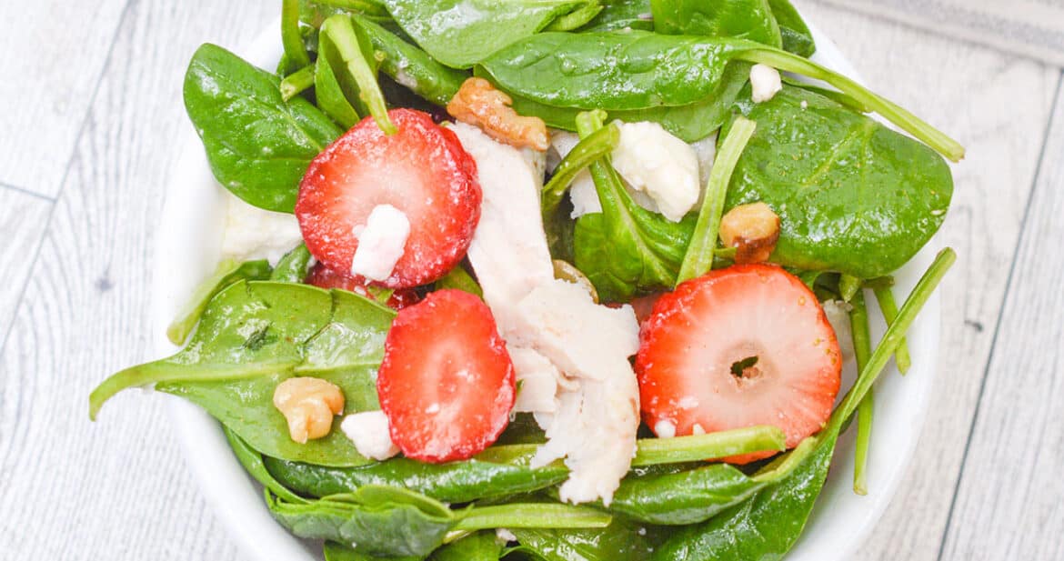 strawberry spinach salad in a white dish
