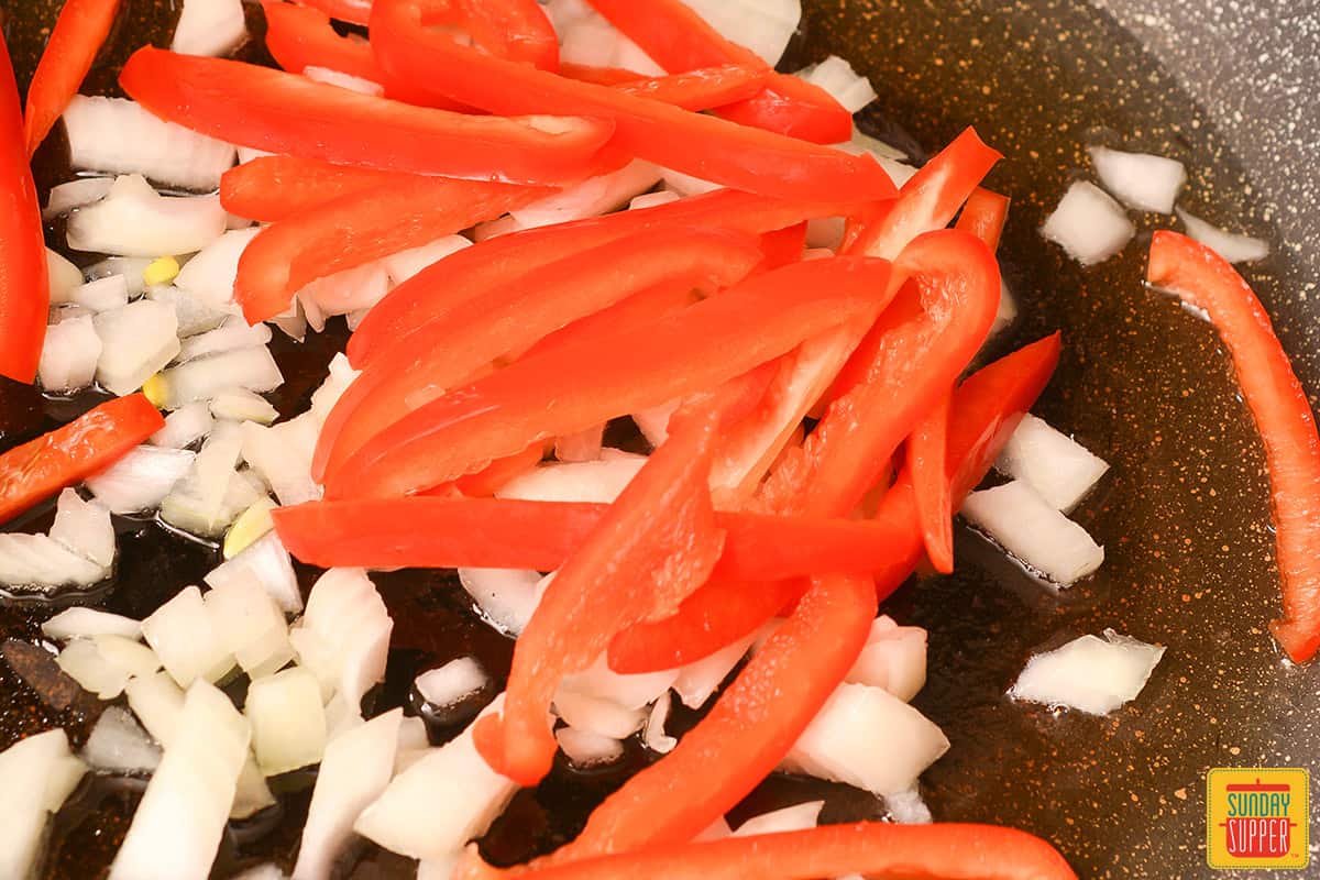 peppers and onions sautéing in a skillet
