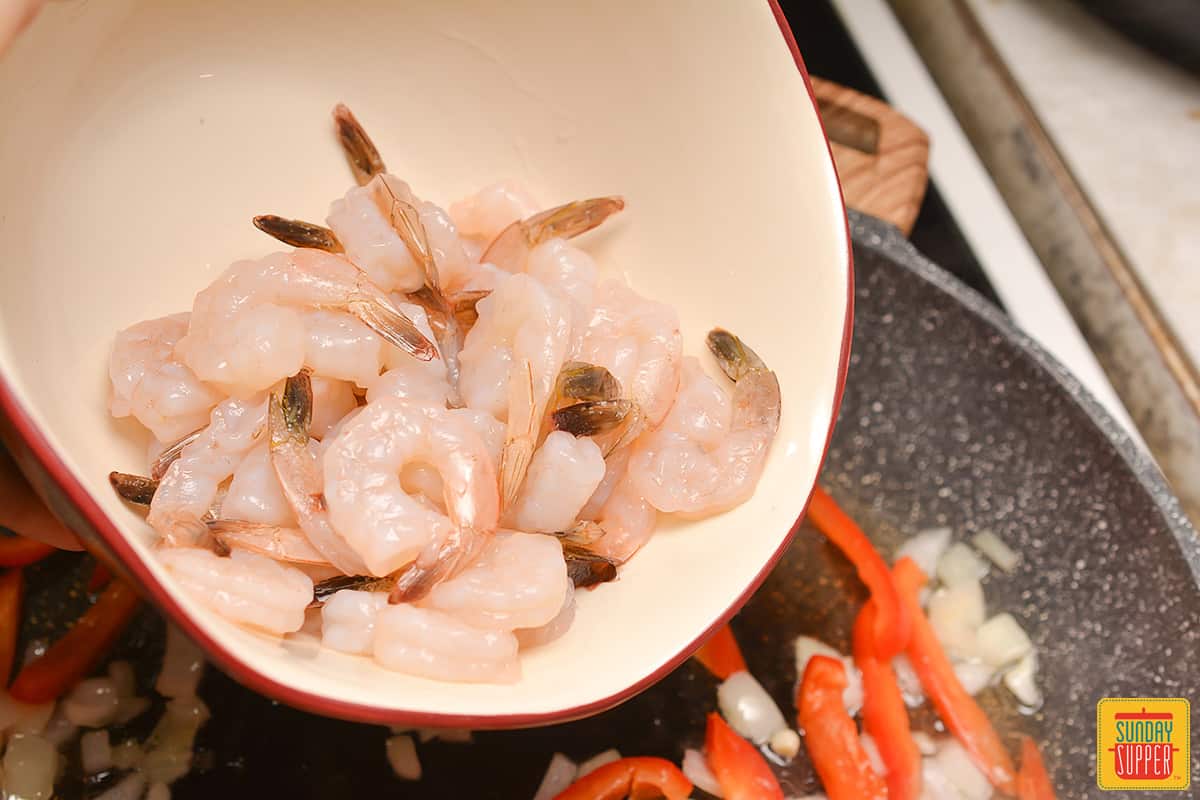 shrimp being added into a skillet