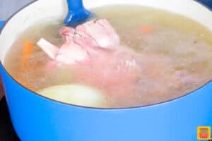 ham stock in a pot being stirred with a spatula