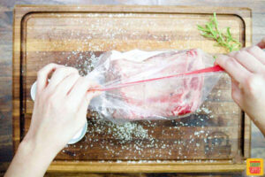 prime rib being placed in a sealed plastic bag