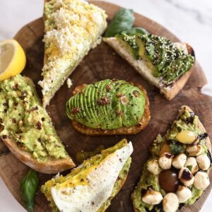 six different kinds of avocado toast on a board