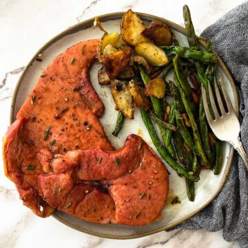 a dinner plate filled with ham steak, sauteed green beans, and roasted potatoes