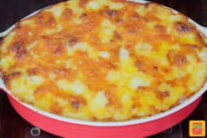 baked ham and potato casserole in a red baking dish