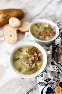 two bowls of ham bone soup with a spoon and fresh bread