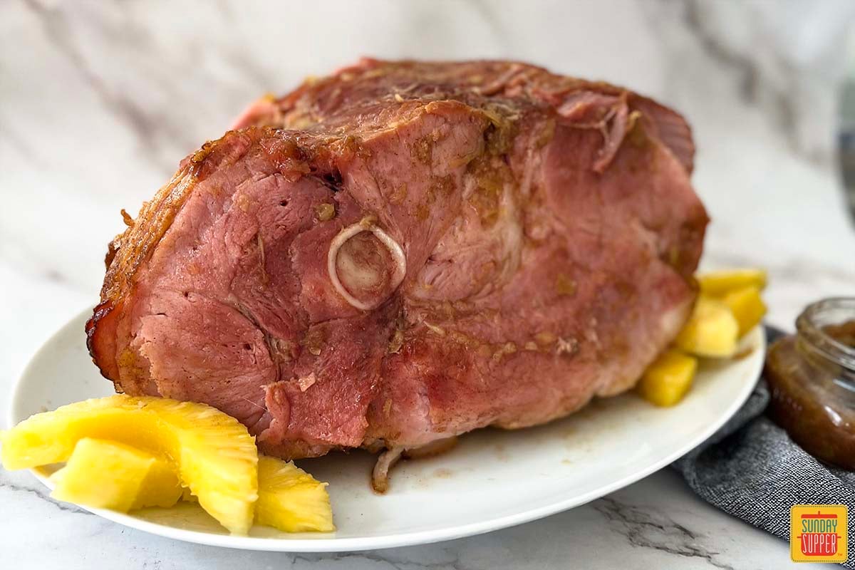 pineapple ham on a white platter with pineapple slices up close