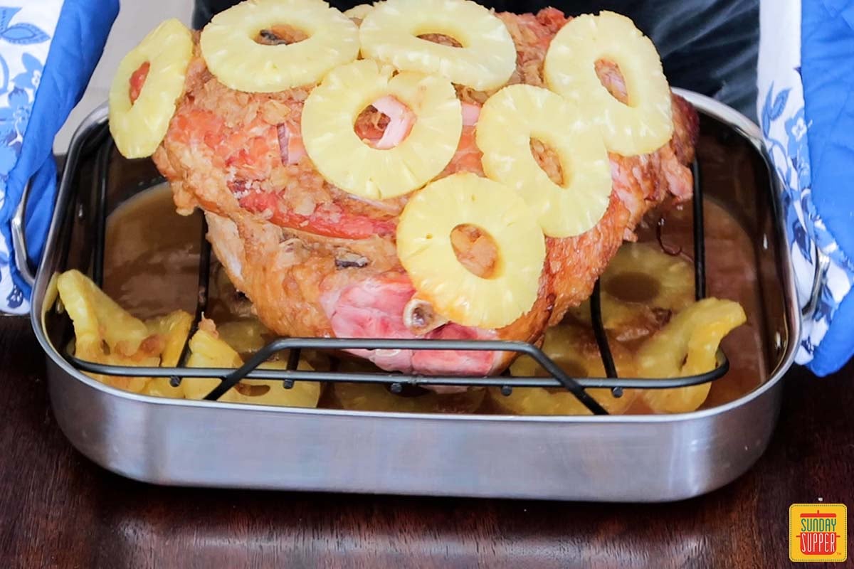 pineapple rings placed over ham on roasting rack ready to bake