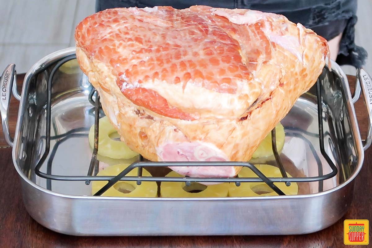 ham on a roasting rack over pineapple slices